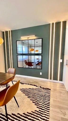 Slat accent wall with integrated lighting beside a black grid-framed interior window.